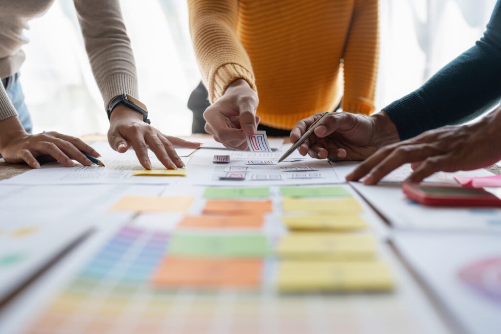 Hands arranging sticky notes and papers on a table during a planning session.